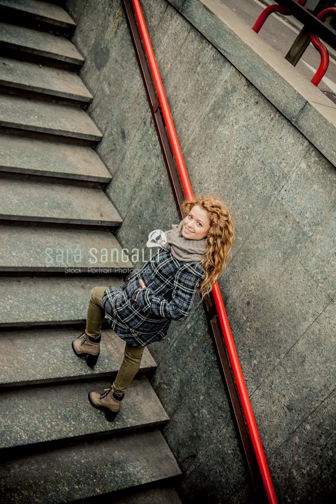 Young blonde woman walking up the stairs of one of Milan metro stations.