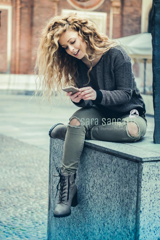 young blonde woman texting on her smartphone