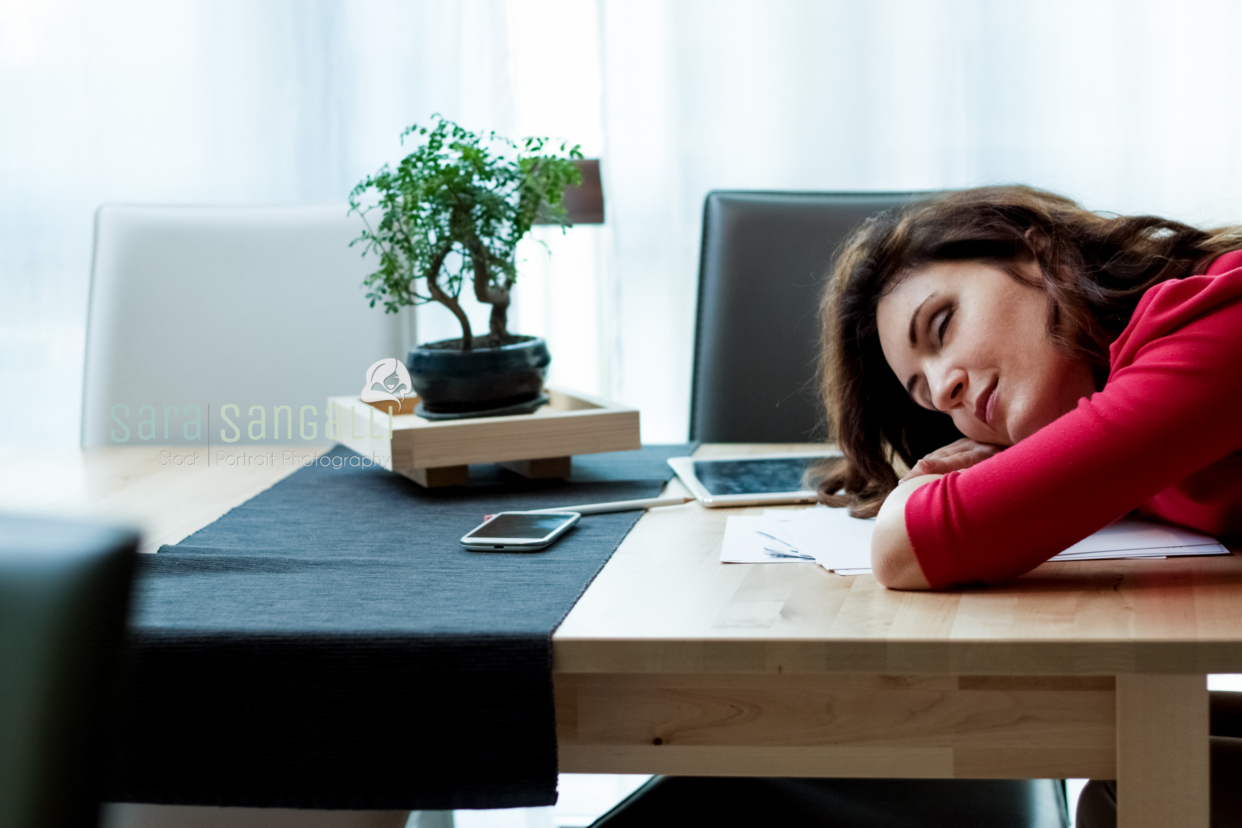 Young caucasian brunette woman sleeping on desk . Indoor setting