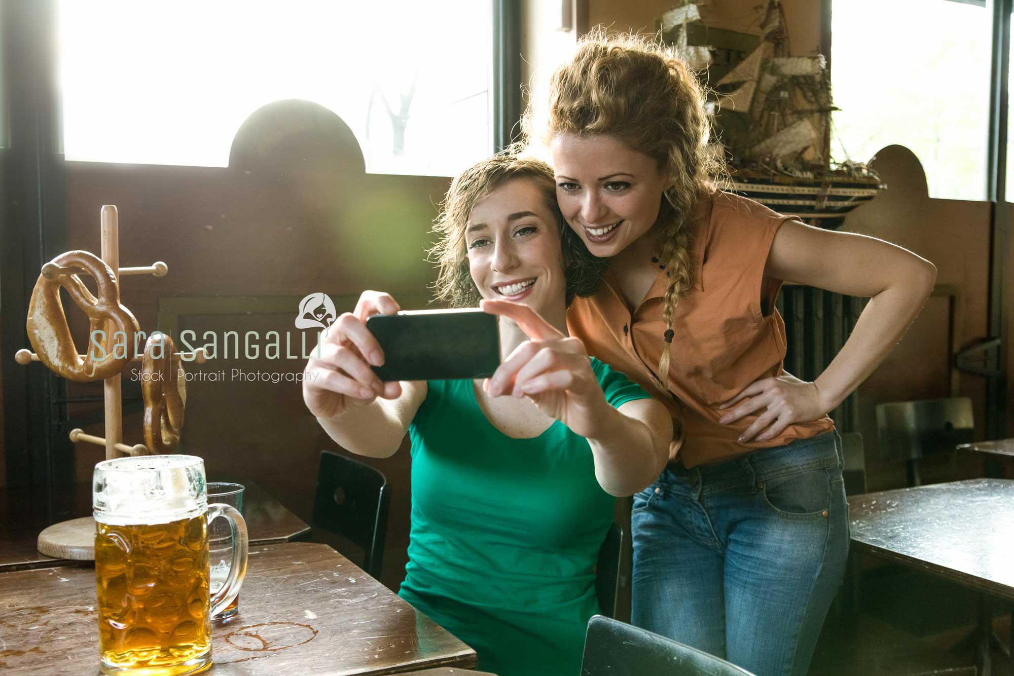 Two girlfriends taking a selfie inside a pub