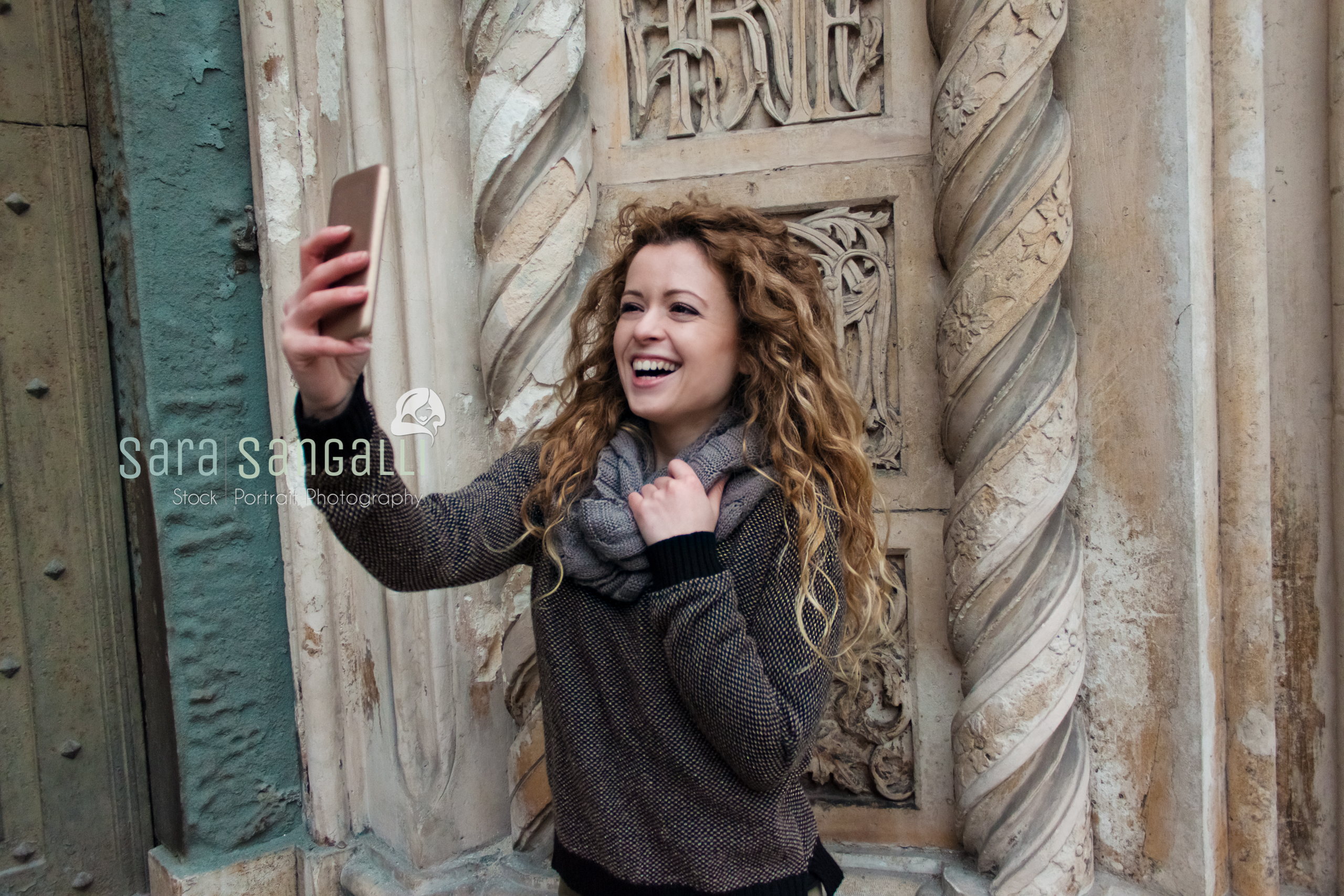 Young blonde girl taking a selfie in front of an ancient building