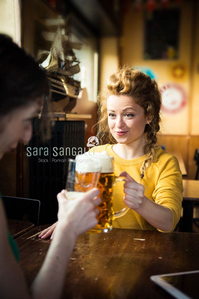 two friends getting toghether drinking beer and laughin, indoor setting