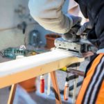 Men doing some woodwork, sanding a wood with sander