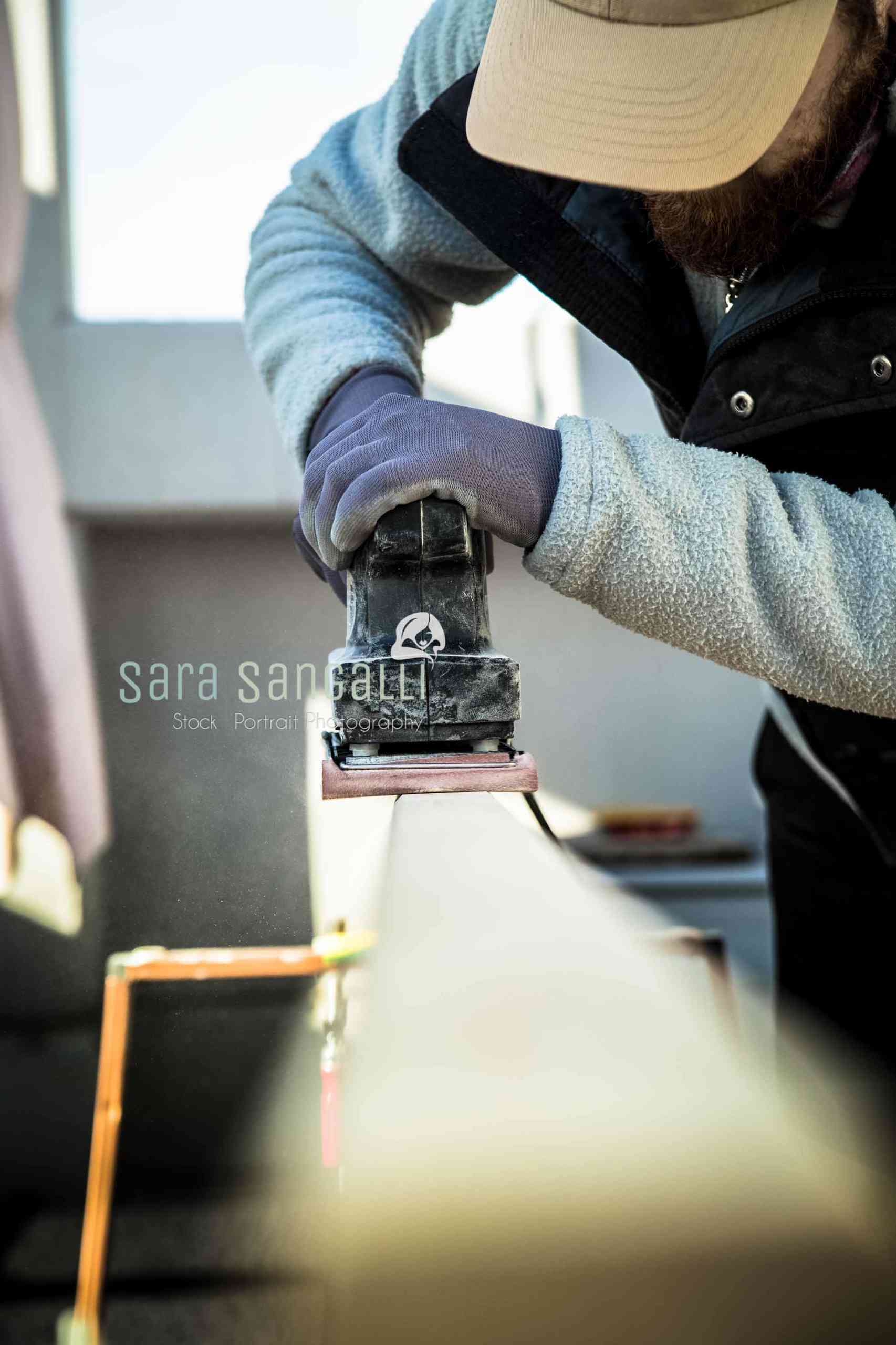 Men doing some woodwork, sanding a wood with sander