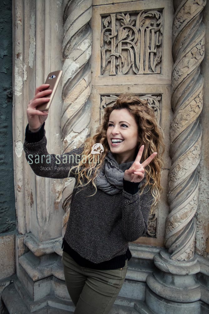 Young blonde girl taking a selfie in front of an ancient building