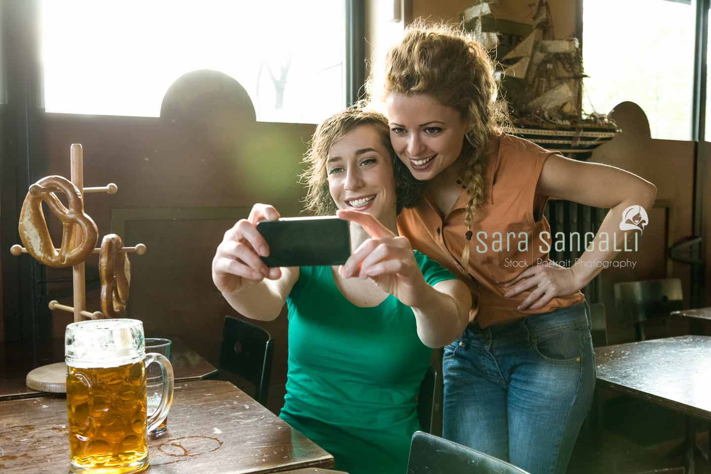 Two girlfriends taking a selfie inside a pub