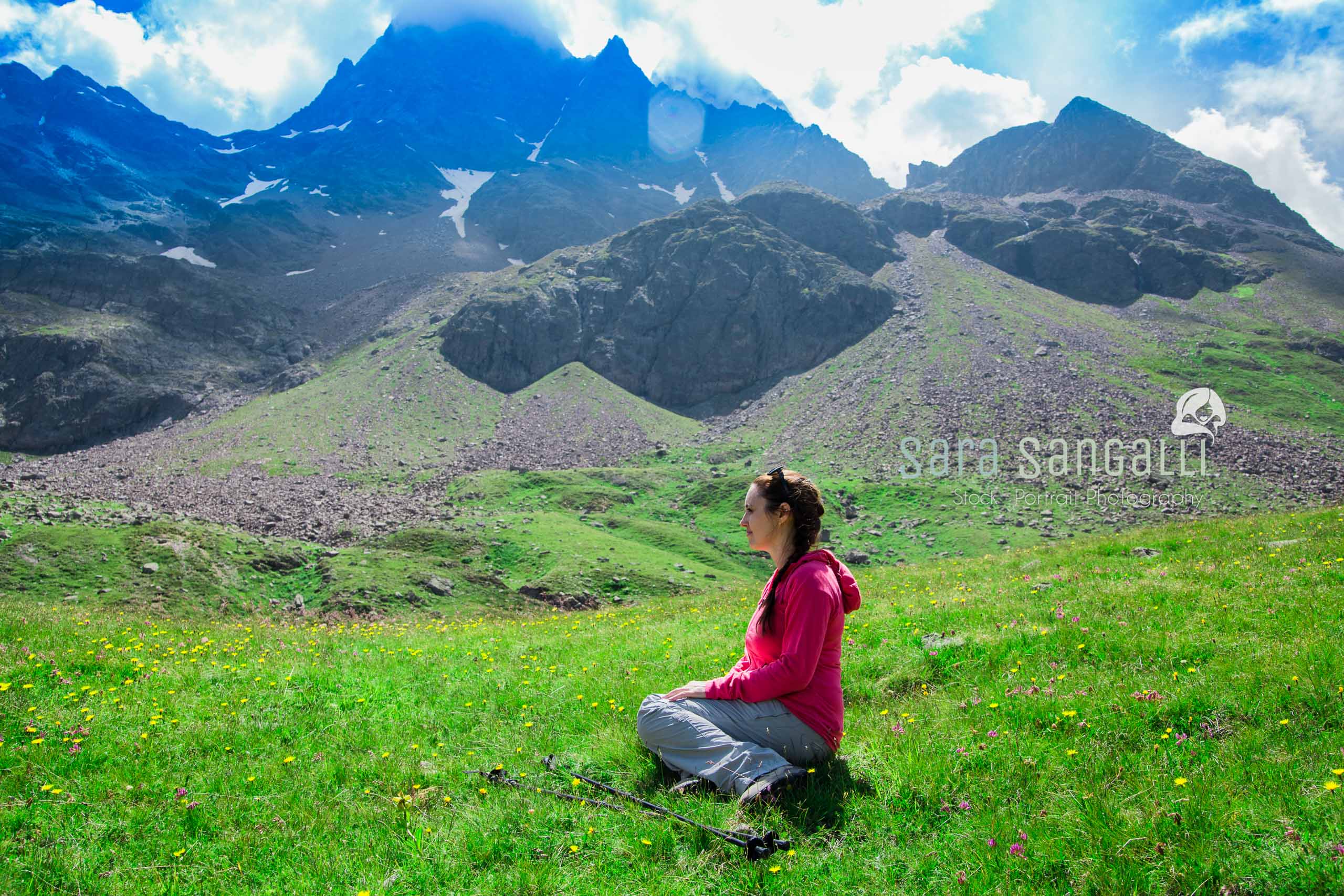 Woman sitting on the grass after a long walk in the mountains