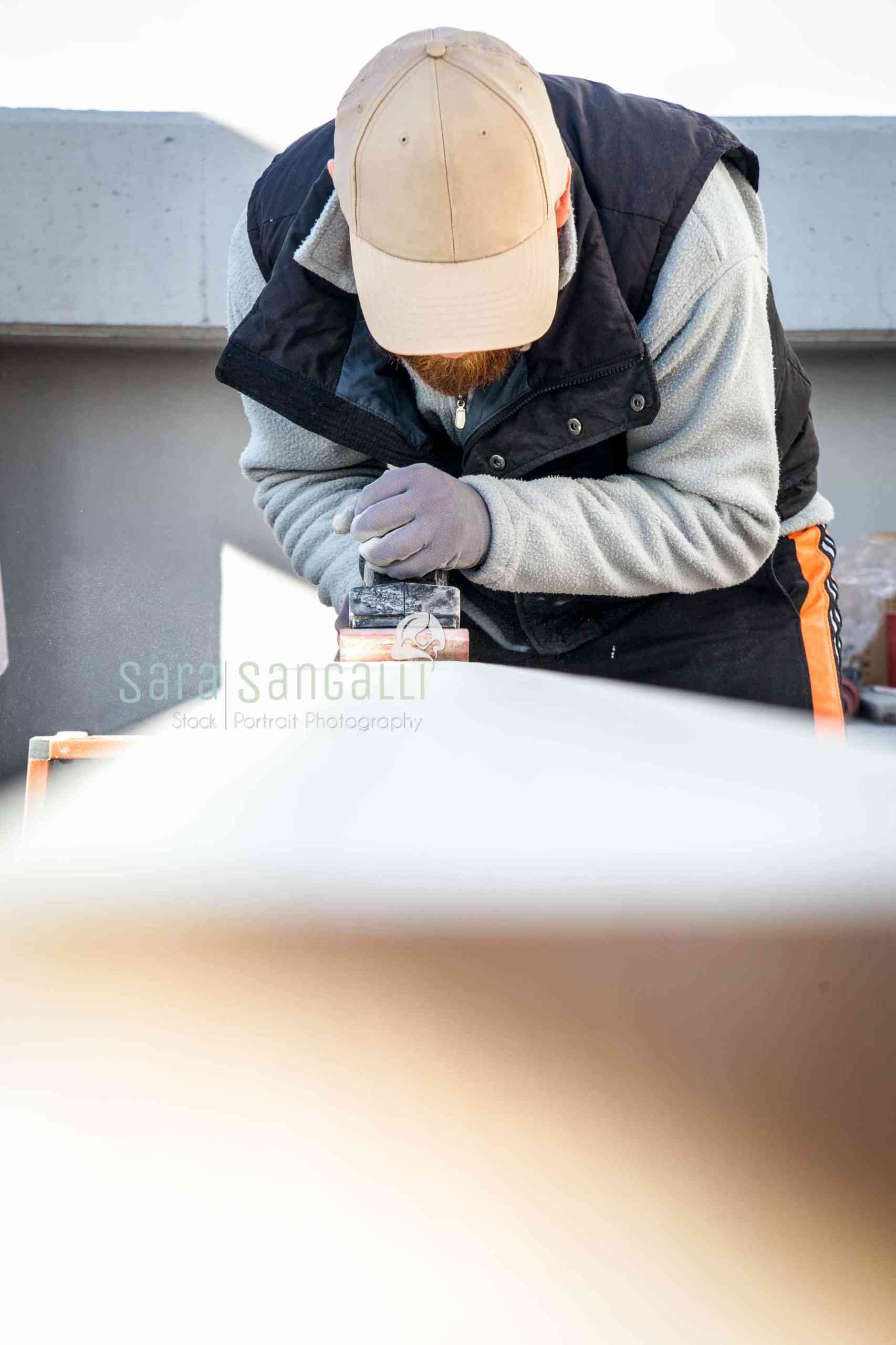 Men doing some woodwork, sanding a wood with sander